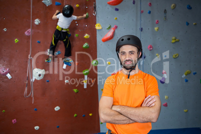 Trainer standing with arms crossed in fitness studio