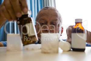 Senior man taking medicines in nursing home