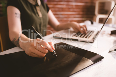 Executive working on stylus while using laptop in office