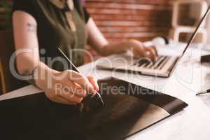 Executive working on stylus while using laptop in office