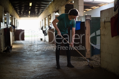 Man using broom to clean the stable