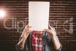 Woman hiding face from blank sheet