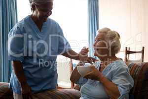 Senior woman talking to nurse while having food