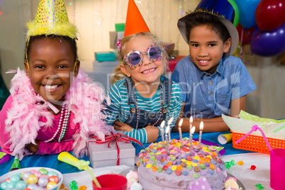 Portrait of cheerful children by birthday cake