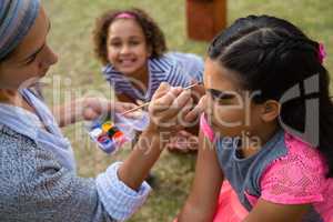 Woman doing face paint to girl