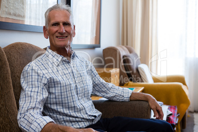 Portrait of senior man sitting on armchair in nursing home
