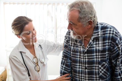 female doctor assisting senior man in walking at nursing home