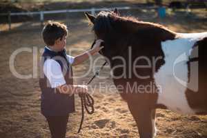 Rider boy caressing a horse in the ranch