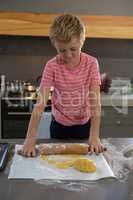 Boy rolling dough in kitchen