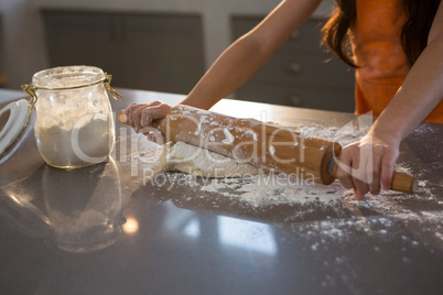 Cropped hands of girl rolling dough