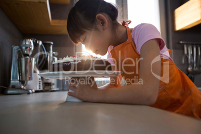 Girl looking at cream cake in kitchen