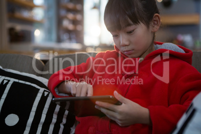 Girl using digital tablet on sofa