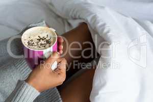 Cropped image of woman having coffee on bed