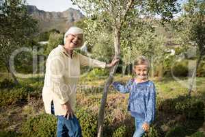 Smiling granddaughter and grandmother standing together in garden