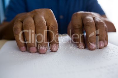 idsection of senior man reading braille book in nursing home