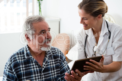 Female doctor showing digital tablet to man in retirement home