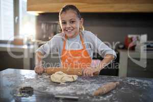 Little girl flattening dough on the kitchen counter