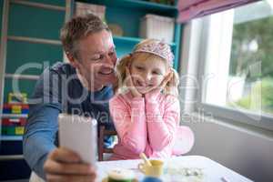 Father taking a selfie of his daughter wearing dressed as fairy