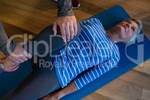 Male physiotherapist helping patient in performing exercise with resistance band