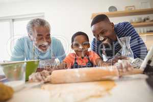 Boy preparing cookie dough with his father and grandfather in kitchen