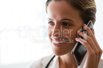 Smiling female doctor talking on mobile phone in nursing home