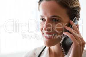 Smiling female doctor talking on mobile phone in nursing home