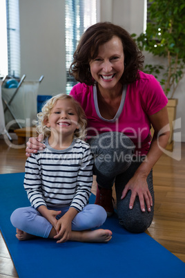Portrait of smiling girl and physiotherapist on yoga mat