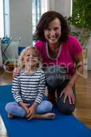 Portrait of smiling girl and physiotherapist on yoga mat
