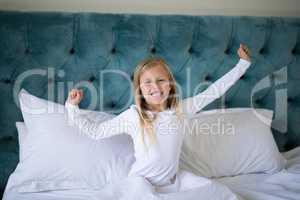 Girl stretching her arms while waking up in bedroom