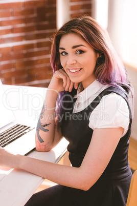 Smiling woman sitting with laptop in office