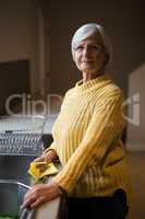 Smiling senior woman standing near kitchen worktop