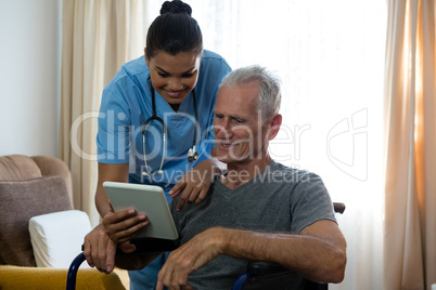 Senior man showing digital tablet to female doctor