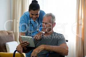 Senior man showing digital tablet to female doctor