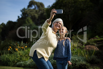 Grandmother and granddaughter taking selfie with mobile phone in garden