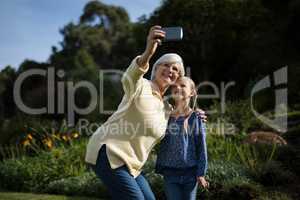 Grandmother and granddaughter taking selfie with mobile phone in garden