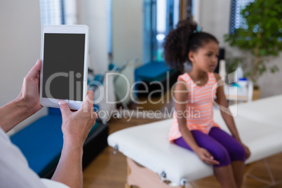 Mid-section of physiotherapist using digital tablet