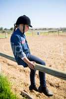 Girl sitting on wooden fence in the ranch