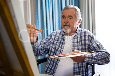Senior man painting while sitting on wheelchair