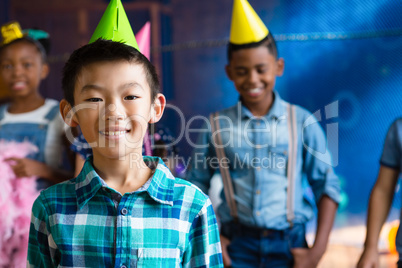 Portrait of smiling boy wearing party hand with friends in background