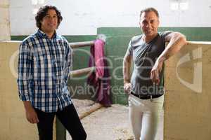 Two male friends standing together in the stable