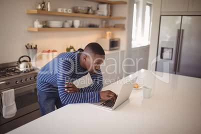 Man using laptop in kitchen