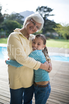 Granddaughter and grandmother embracing near the pool