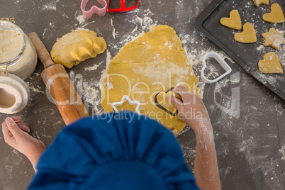 Cropped hands of boy preparing cookies in kitchen