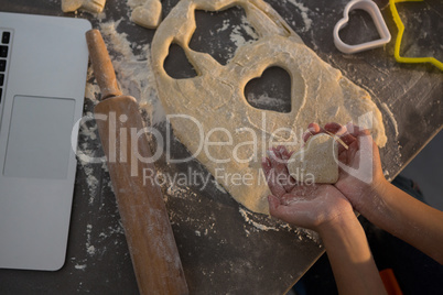 Cropped hands of girl holding heart shape dough