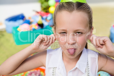 Close up portrait of girl holding ears while sticking out tongue