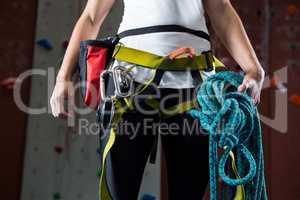 Woman in safety harness holding rope in fitness studio