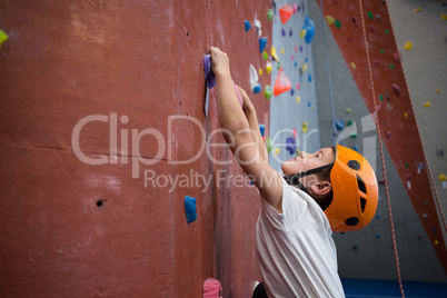 Boy practicing rock climbing in fitness studio