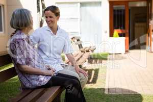 Senior woman talking to doctor while sitting on bench