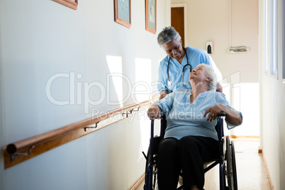 Nurse talking while pushing patient sitting in wheelchair