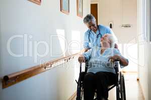 Nurse talking while pushing patient sitting in wheelchair